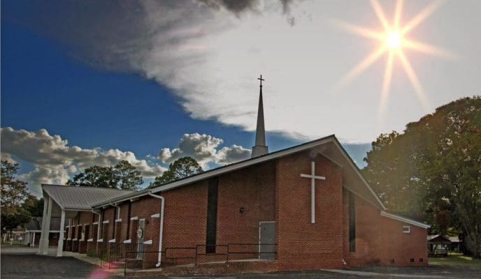 The exact original photograph of Carroll Memorial Baptist Church, with its brick sanctuary, steeple, and sunlight